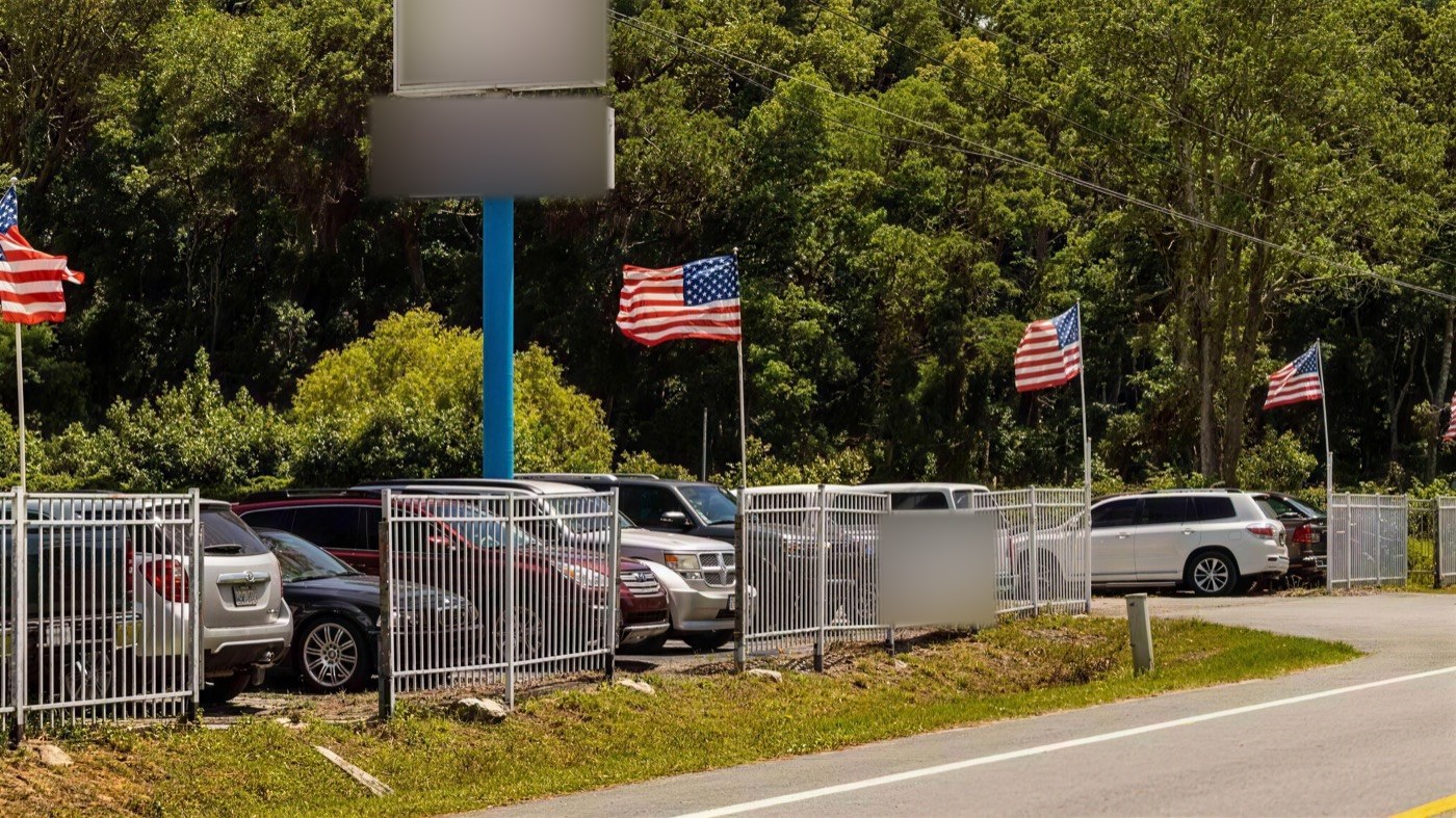 Fenced parking lot on Airport Road in Jacksonville, Florida — the future EZ Truck Parking Jacksonville yard, flying American flags.